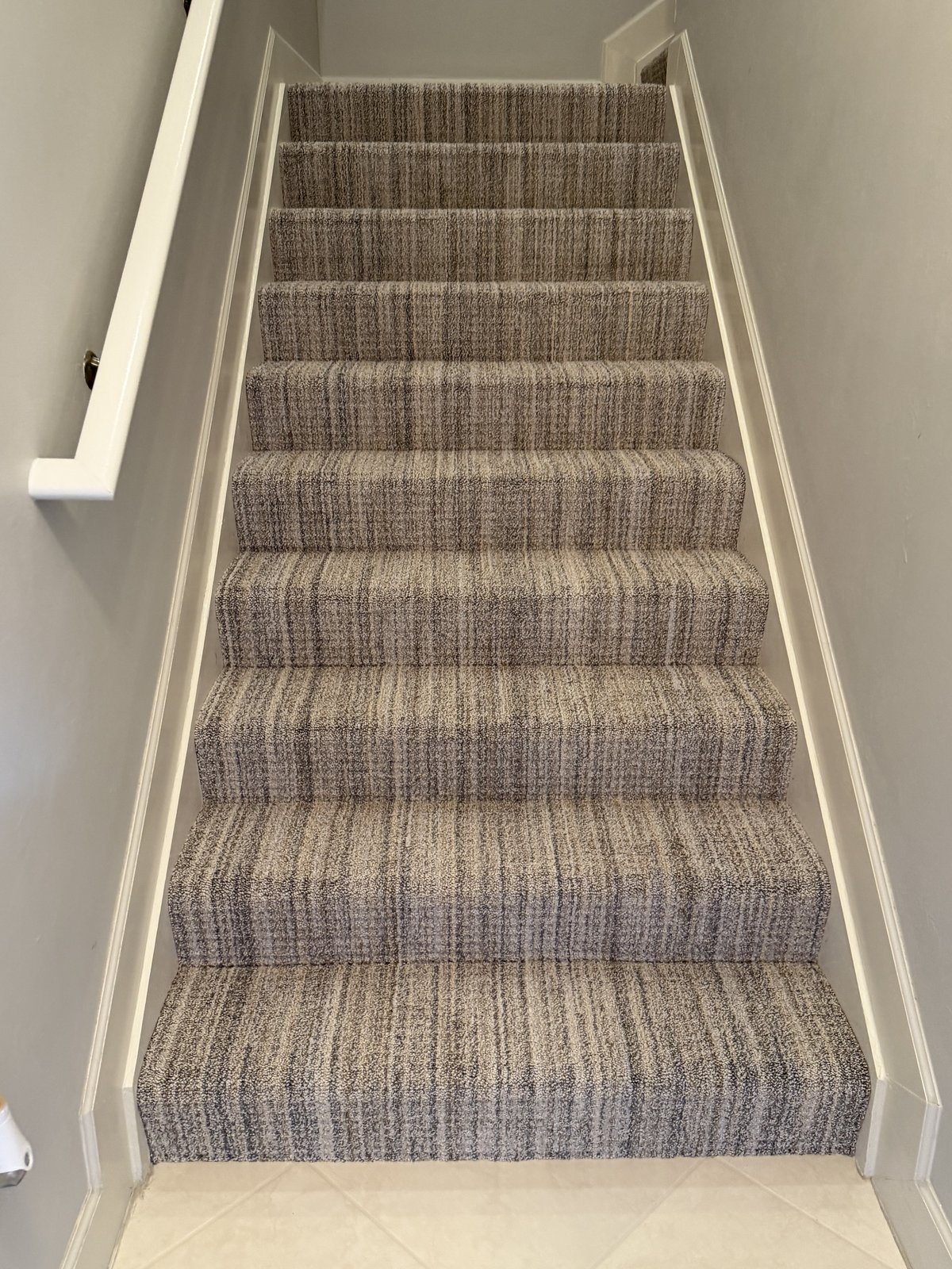 Striped carpet staircase fitted between crisp white stair walls